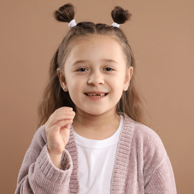 Little girl holding tooth that came out in her hand, representing how to make losing a tooth fun