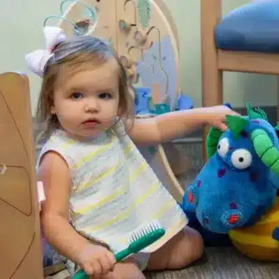 Your childโs first pediatric dental visit in wilmington nc 3 Little girl playing with toys on the floor, representing your childโs first pediatric dental visit in wilmington nc