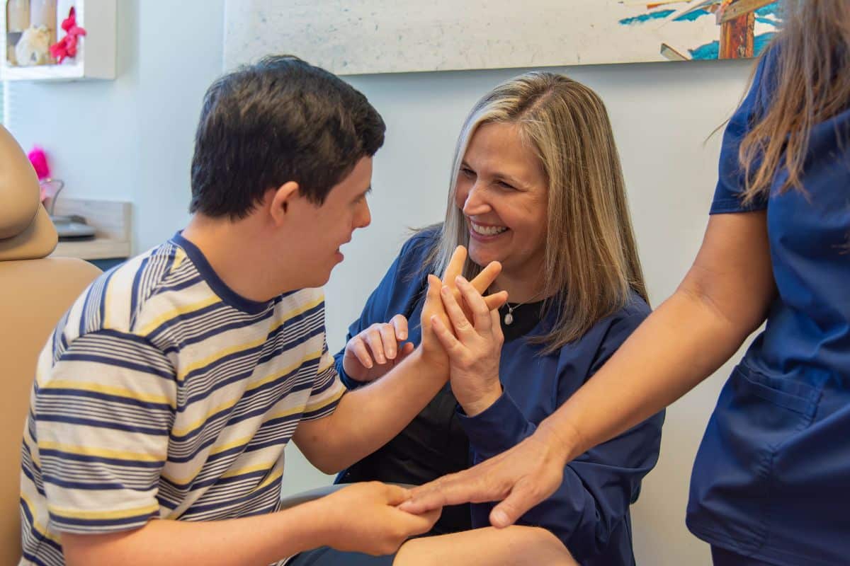Dental hygienist high-fiving a happy child with special healthcare needs at Wilmington Pediatric Dentistry
