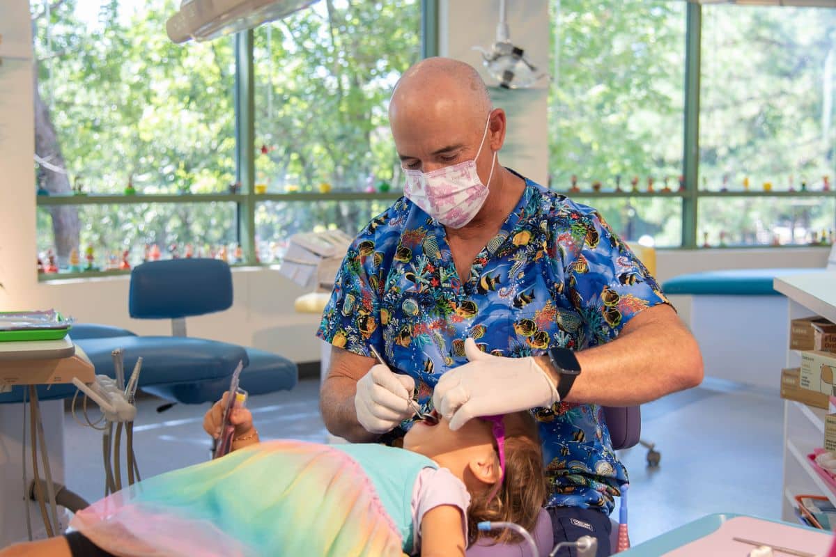 Dentist carefully performing treatment in a child’s mouth for extractions and space maintainers at Wilmington Pediatric Dentistry