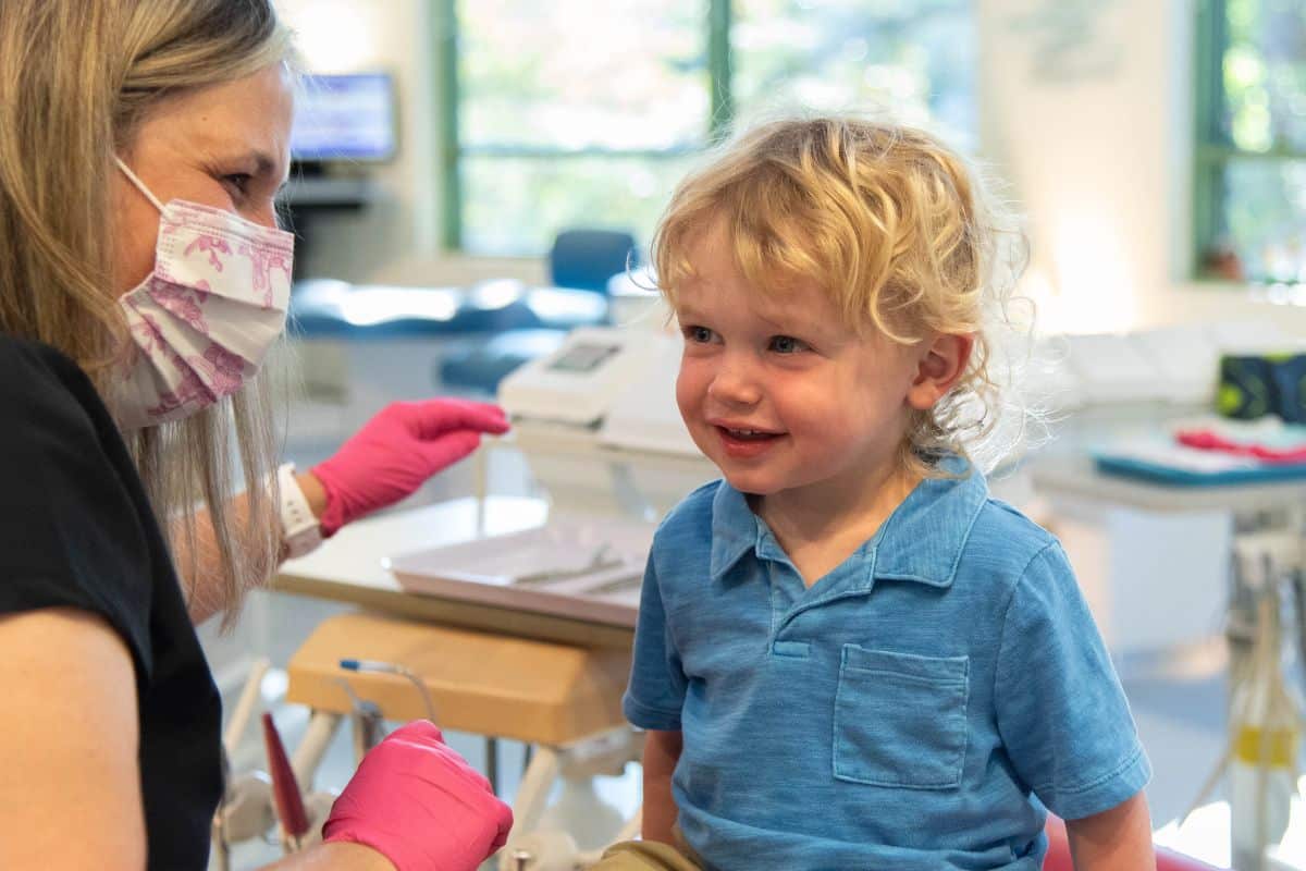 Curly-haired blonde little boy smiling at Wilmington Pediatric Dentistry after a pulpotomy treatment