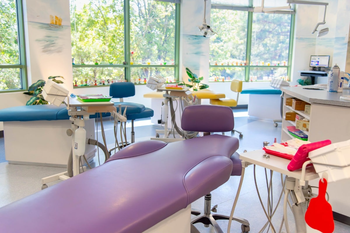 Colorful pediatric dental exam room with bright treatment chairs and large windows