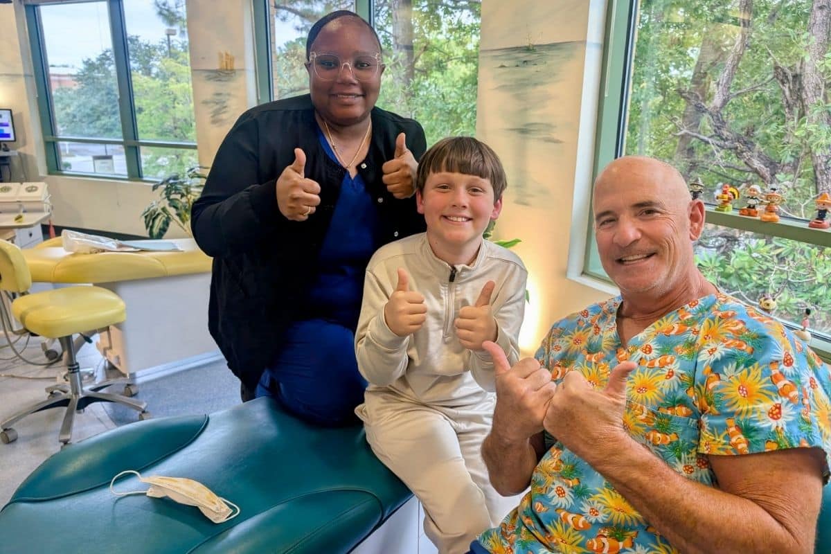 Pediatric dentist and dental assistant celebrating with a young patient after a successful dental visit at Wilmington Pediatric Dentistry in Wilmington, North Carolina.